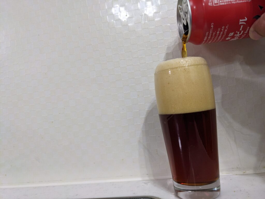 グラスに泡が溢れるまで「悪魔のビールレッドセッションIPA」を注いでいる