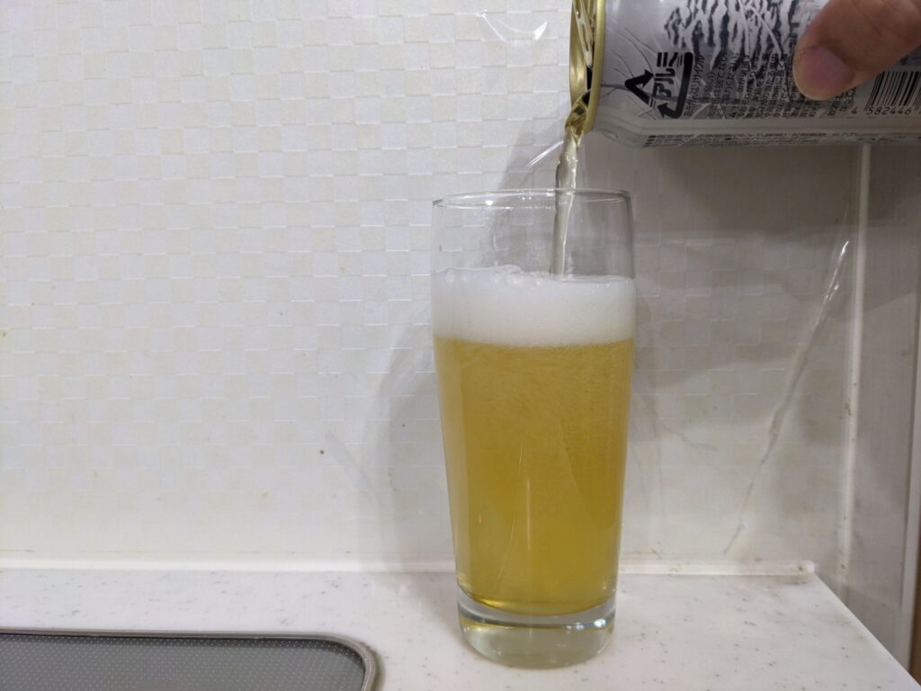 8割程グラスに「THE軽井沢ビール冬紀行プレミアム」を注いでいる