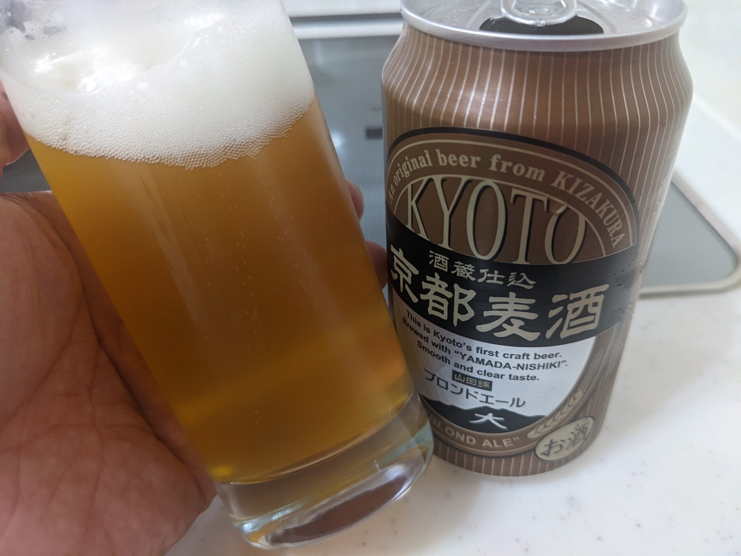 「京都麦酒ブロンドエール」が入ったグラスを傾けているところ