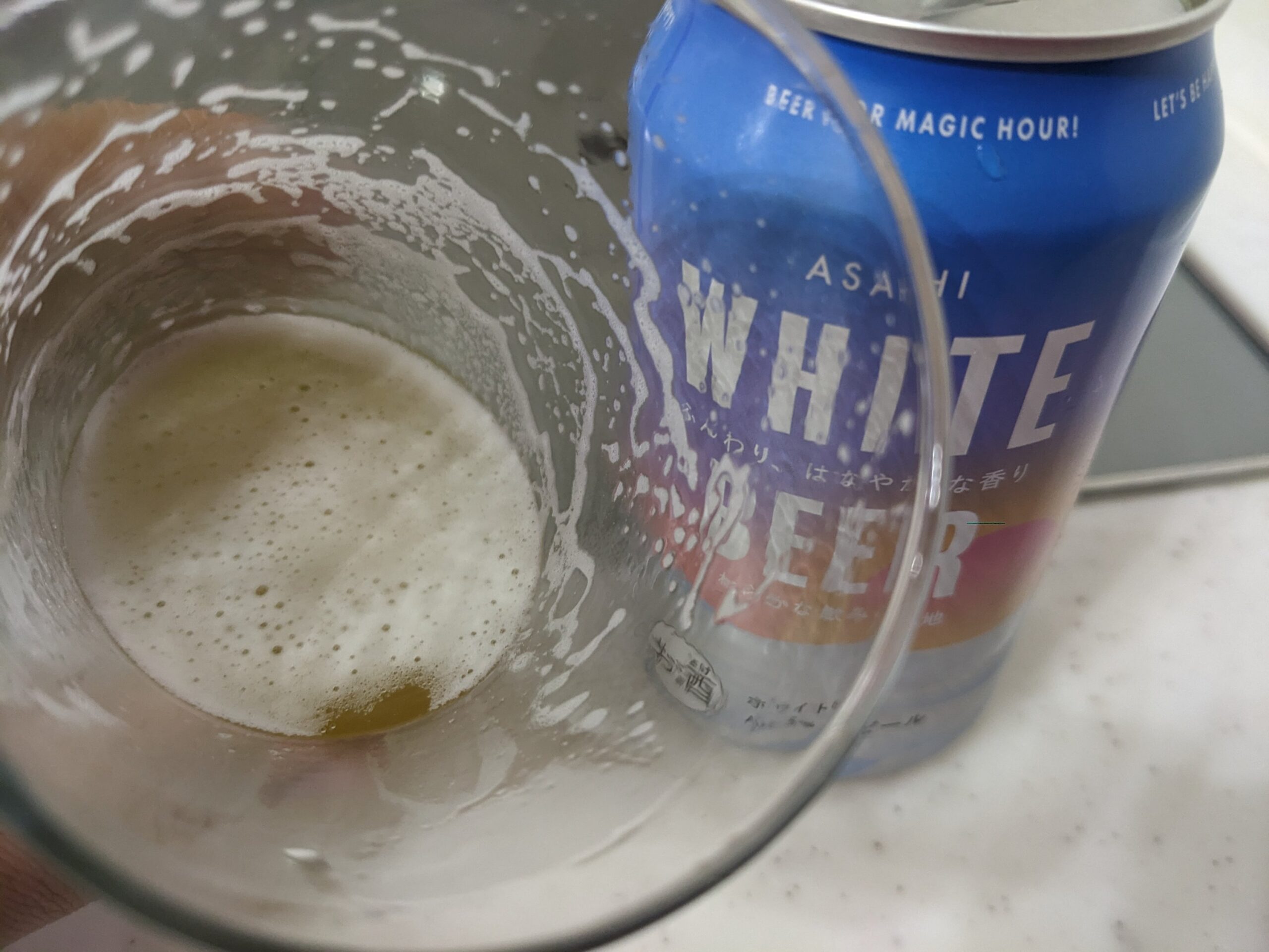 「アサヒホワイトビール（ASAHI WHITE BEER） 」が入ったグラスを傾けているところ